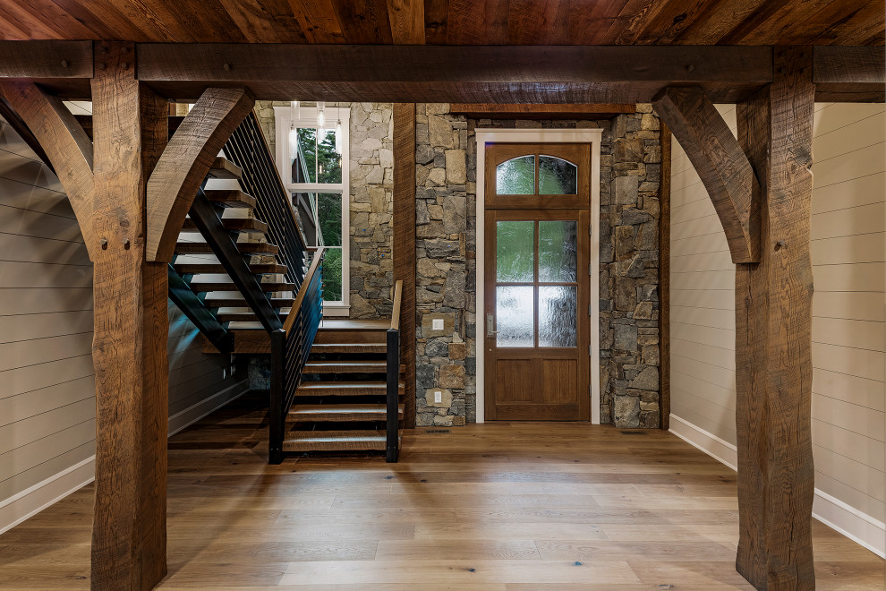 Großes Uriges Foyer mit grauer Wandfarbe, braunem Holzboden, Einzeltür, hellbrauner Holzhaustür, grauem Boden, gewölbter Decke und Holzdielenwänden in Sonstige