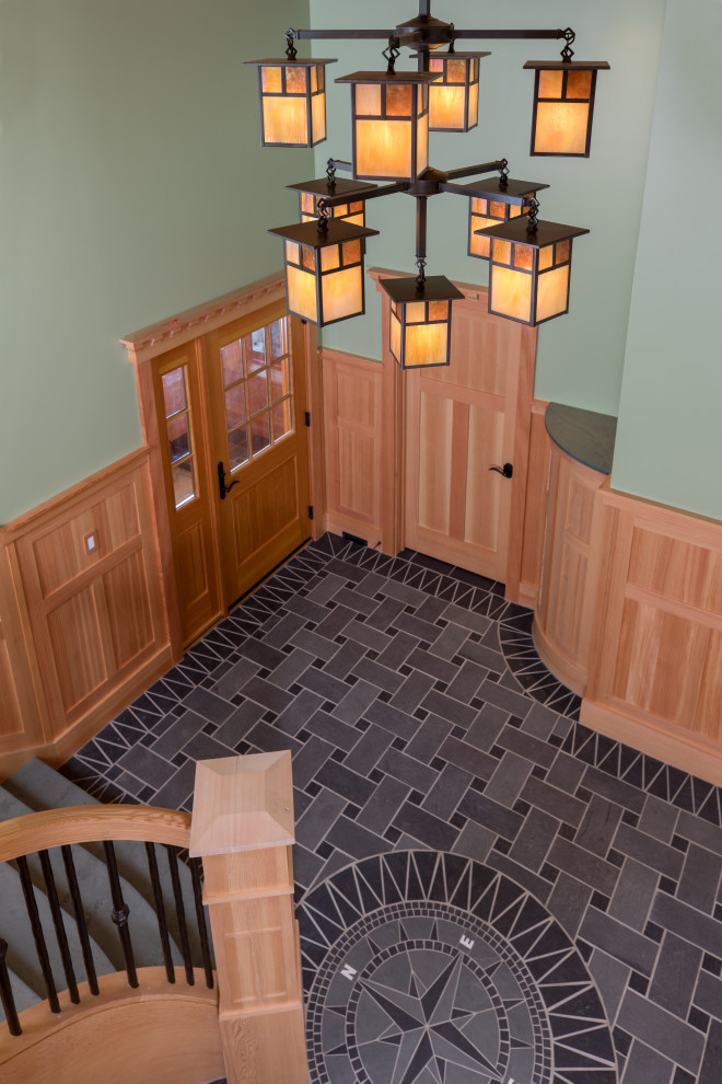 This is an example of a scandi foyer in Portland Maine with green walls, slate flooring, a single front door, a medium wood front door and black floors.