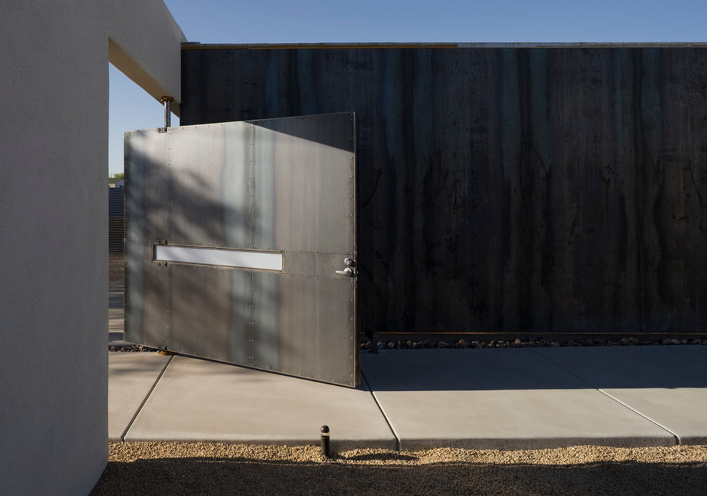 Modelo de entrada moderna con suelo de cemento, puerta pivotante y puerta metalizada