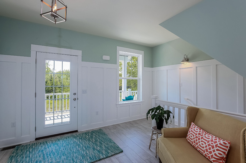 Imagen de distribuidor costero grande con suelo de madera clara, paredes azules, puerta simple, puerta blanca y suelo beige