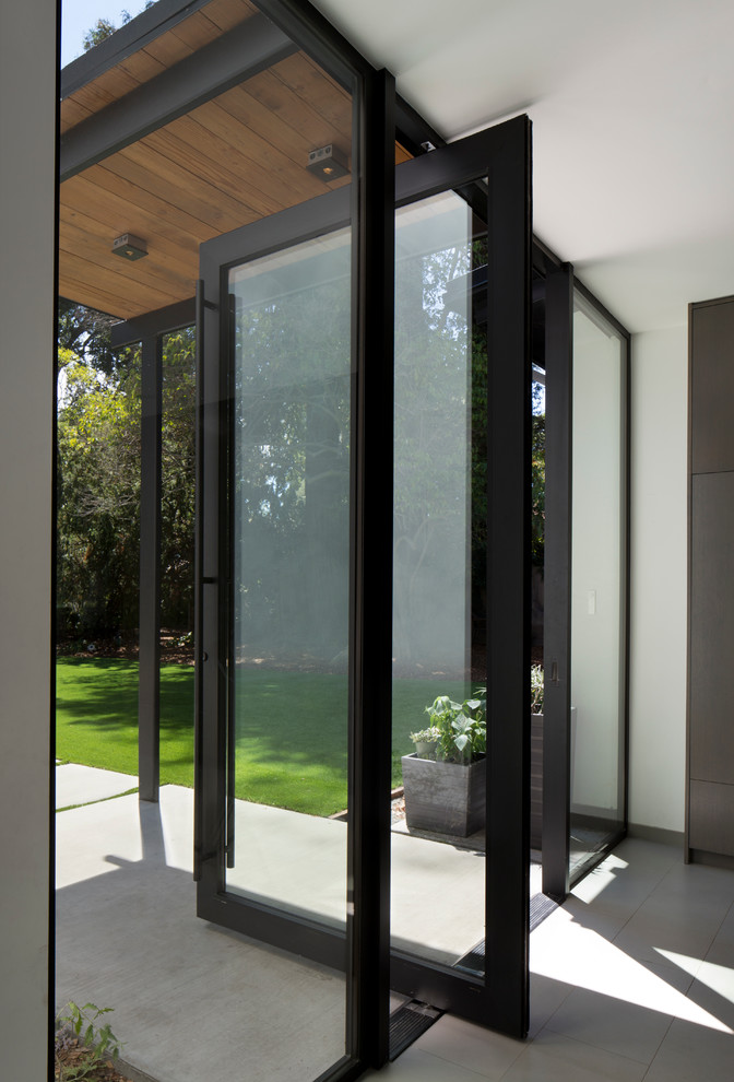 Example of a trendy slate floor pivot front door design in San Francisco with white walls and a glass front door