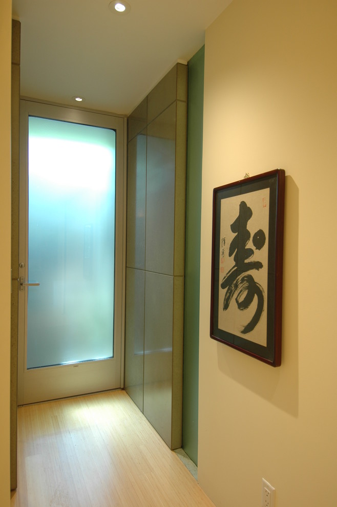 Foto di un piccolo ingresso con vestibolo minimalista con pareti gialle, pavimento in bambù, una porta singola e una porta in vetro