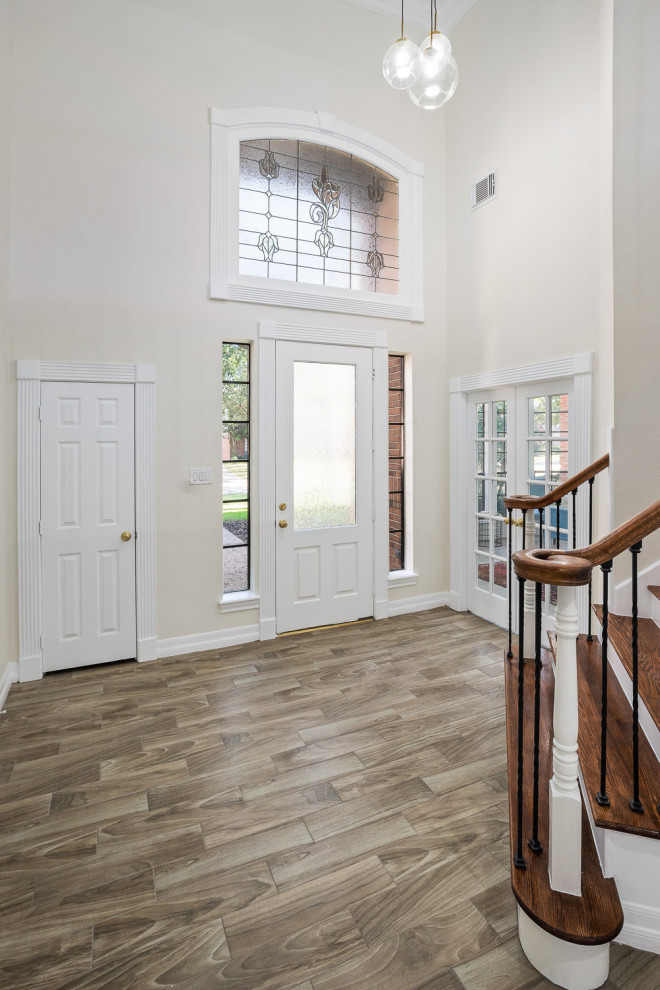 Esempio di una porta d'ingresso tradizionale di medie dimensioni con pareti beige, pavimento in gres porcellanato, una porta singola, una porta bianca e pavimento marrone