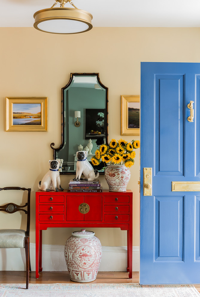 Inspiration for a mid-sized timeless medium tone wood floor and brown floor entryway remodel in Boston with yellow walls and a blue front door
