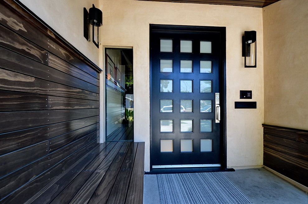 Imagen de puerta principal retro grande con paredes beige, suelo de cemento y puerta de madera oscura