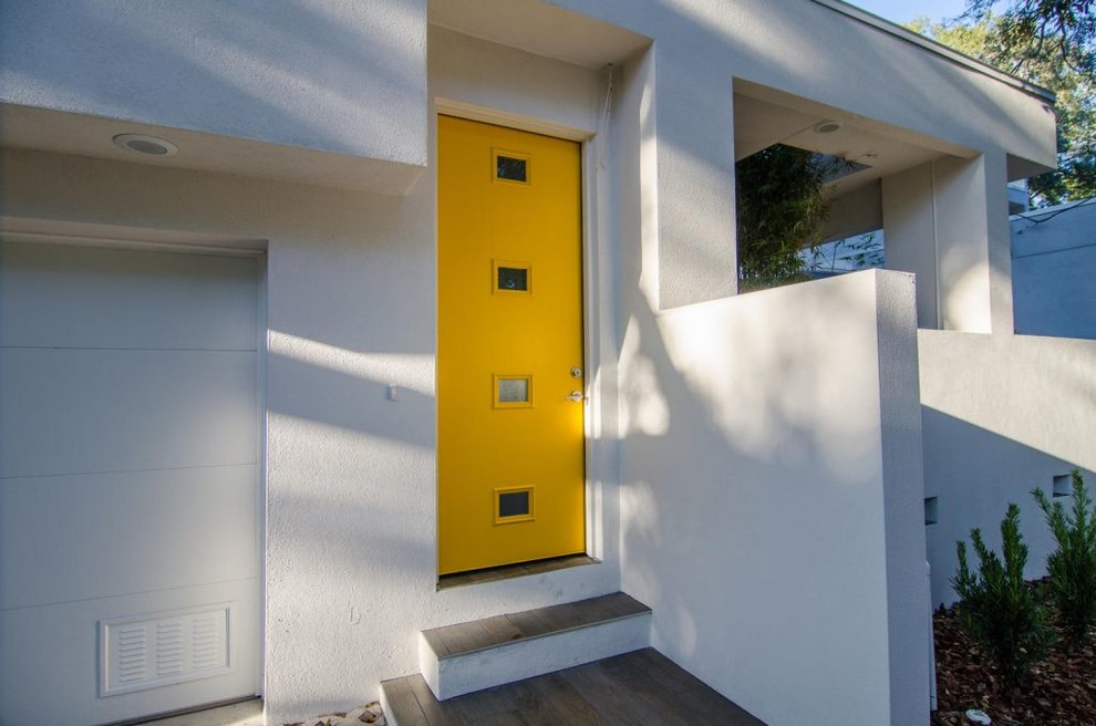 Aménagement d'une très grande porte d'entrée contemporaine avec un mur beige, un sol en bois brun, une porte simple, une porte jaune et un sol marron.