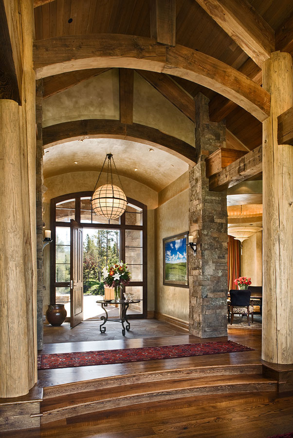 他の地域にある広いラスティックスタイルのおしゃれな玄関ホール (ベージュの壁、無垢フローリング、濃色木目調のドア、茶色い床) の写真