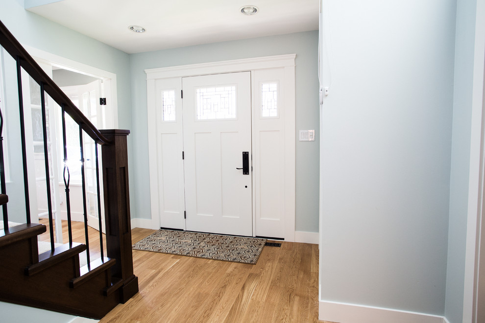 Ejemplo de distribuidor clásico renovado de tamaño medio con paredes verdes, suelo de madera clara, puerta simple y puerta blanca