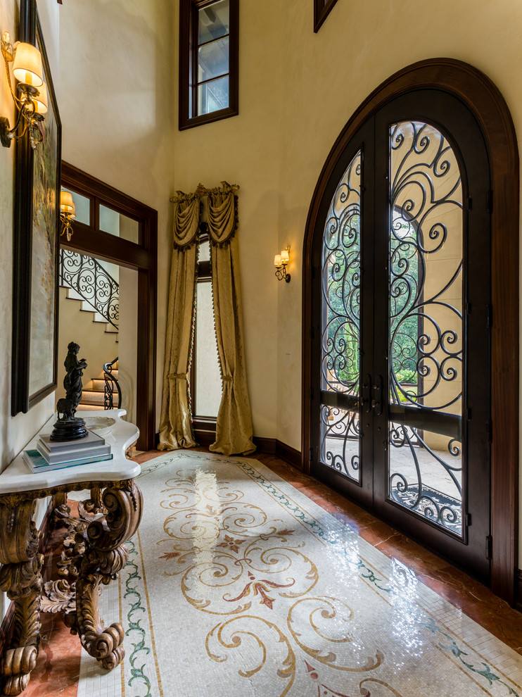 Example of a tuscan entryway design in Other with beige walls and a dark wood front door