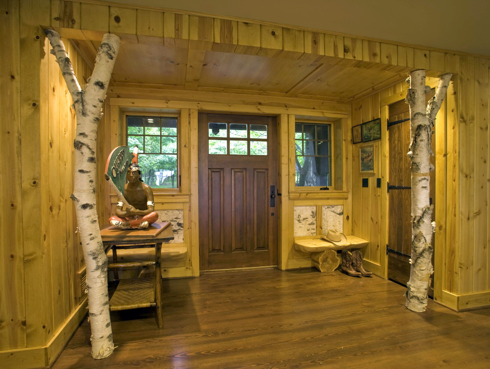 Cette image montre un hall d'entrée chalet de taille moyenne avec un mur beige, parquet foncé, une porte simple et une porte en bois brun.