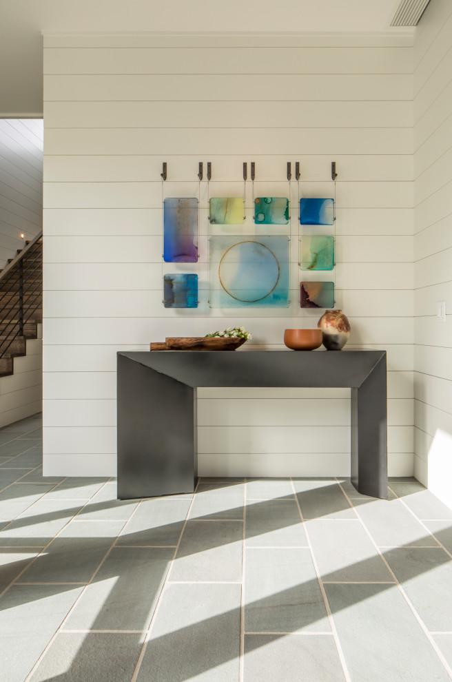 Immagine di un ingresso minimalista di medie dimensioni con pareti bianche, pavimento in pietra calcarea, una porta singola, una porta in legno bruno e pavimento grigio