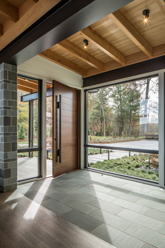 Inspiration pour un grand hall d'entrée design en bois avec un mur blanc, un sol en calcaire, une porte simple, une porte en bois brun et un sol gris.