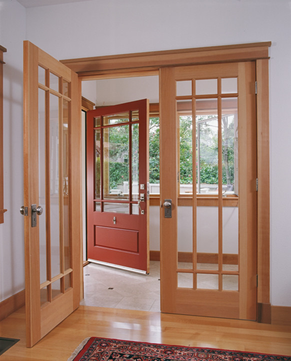 Ispirazione per un corridoio american style con pareti bianche, parquet chiaro, una porta a due ante e una porta in legno chiaro