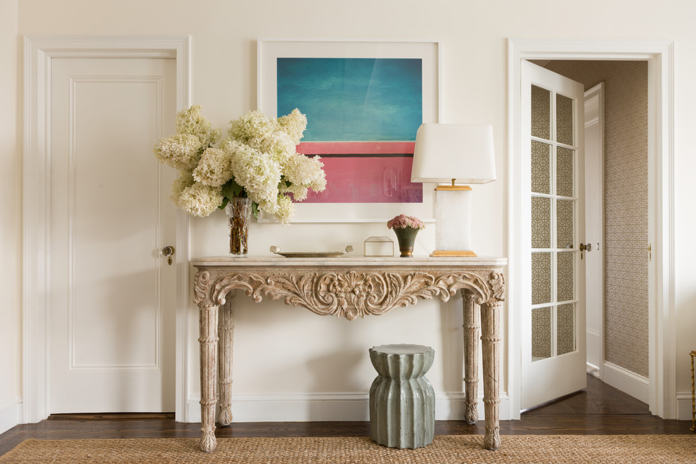 Cette image montre une entrée traditionnelle avec un mur blanc et parquet foncé.