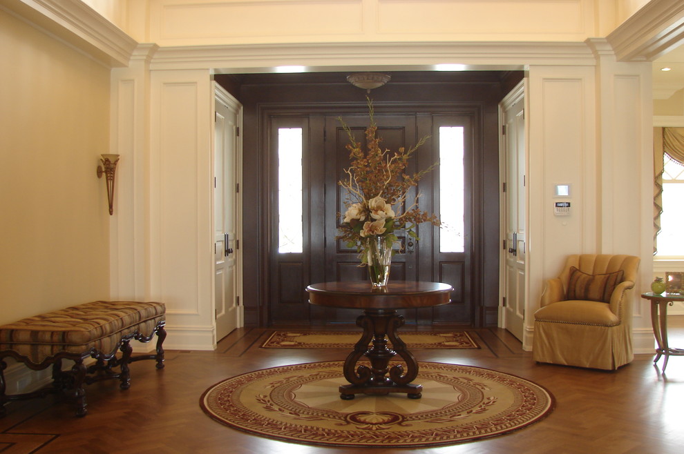 Modelo de entrada tradicional grande con suelo de madera en tonos medios, puerta simple y puerta de madera oscura