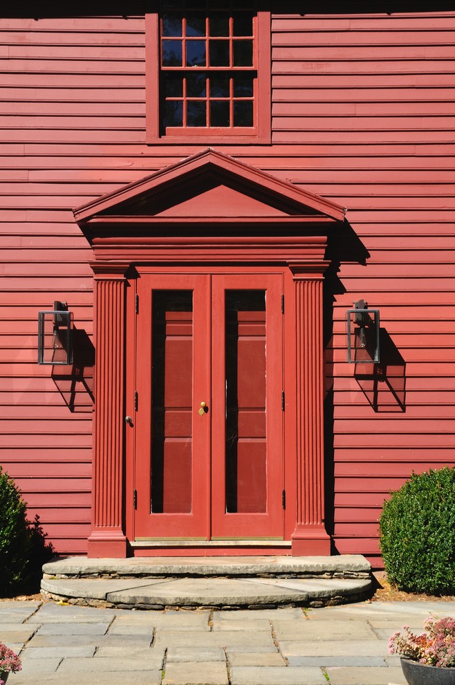 Inredning av en klassisk mellanstor ingång och ytterdörr, med röda väggar, skiffergolv, en dubbeldörr och en röd dörr