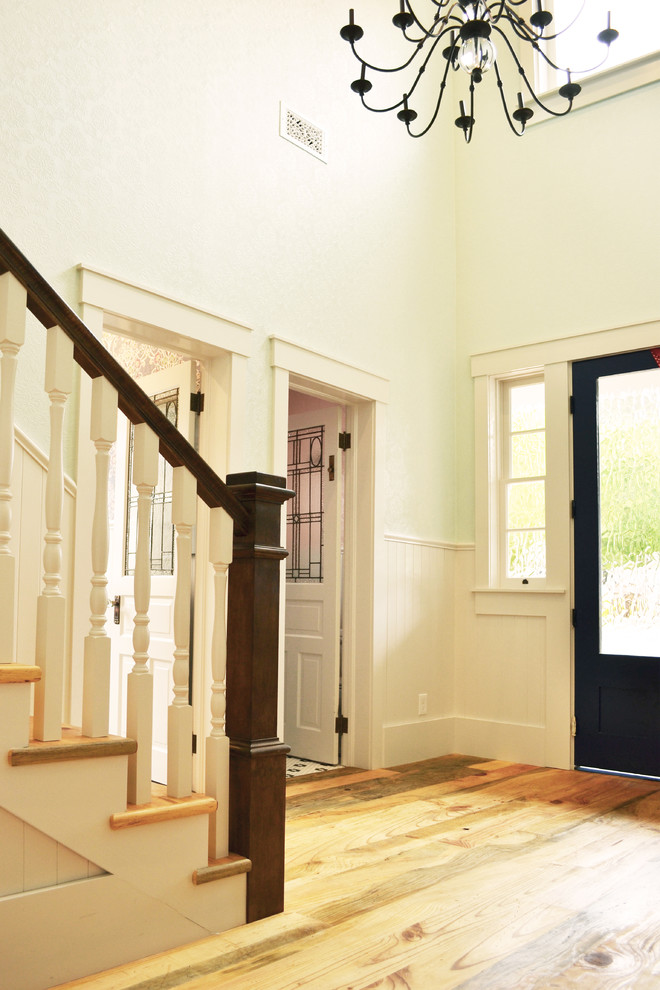 Modelo de puerta principal de estilo de casa de campo de tamaño medio con paredes azules, suelo de madera clara, puerta simple, puerta azul y suelo marrón