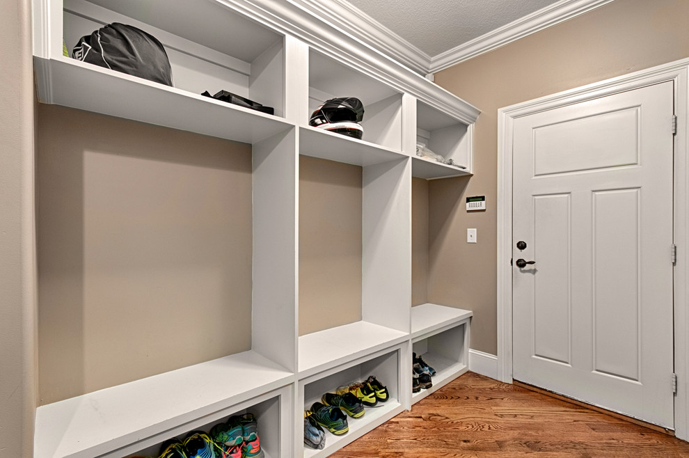 Inspiration for a small timeless medium tone wood floor entryway remodel in Other with beige walls and a white front door