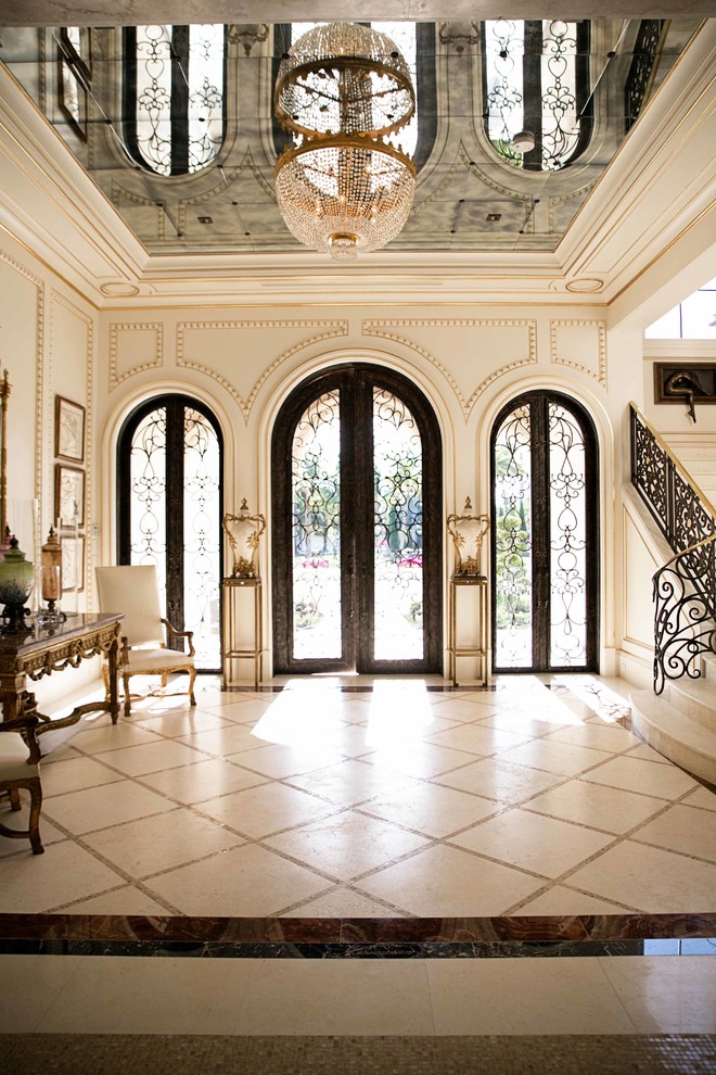 Inspiration pour un hall d'entrée méditerranéen avec une porte double, une porte en bois foncé, un mur blanc et un sol en travertin.