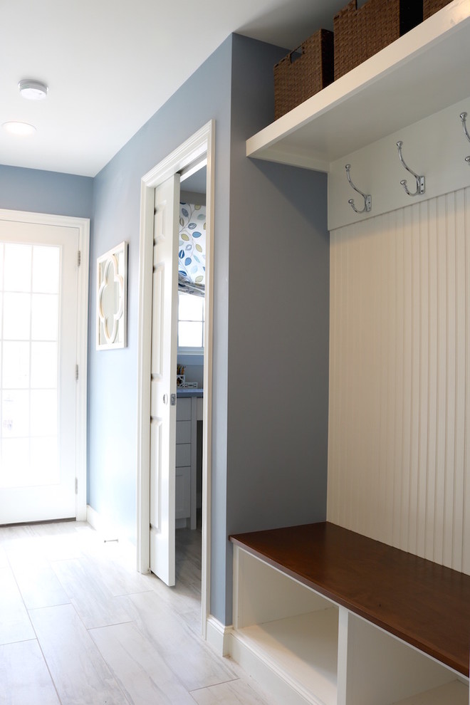 Aménagement d'une entrée classique de taille moyenne avec un vestiaire, un mur bleu, un sol en carrelage de porcelaine, une porte simple et une porte blanche.