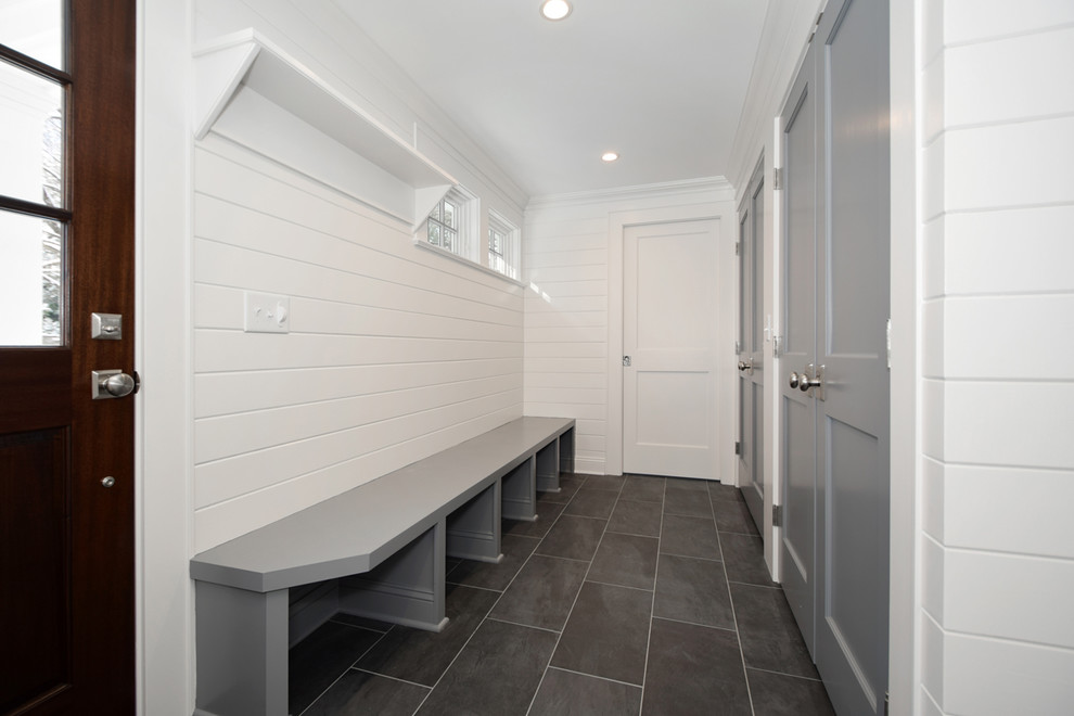 Idées déco pour une entrée classique avec un mur blanc, une porte pivot, une porte en bois foncé et un sol noir.