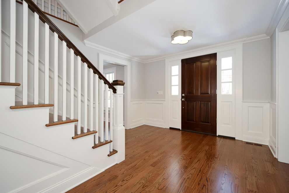 Design ideas for a traditional entrance in New York with grey walls, a pivot front door, a dark wood front door and brown floors.