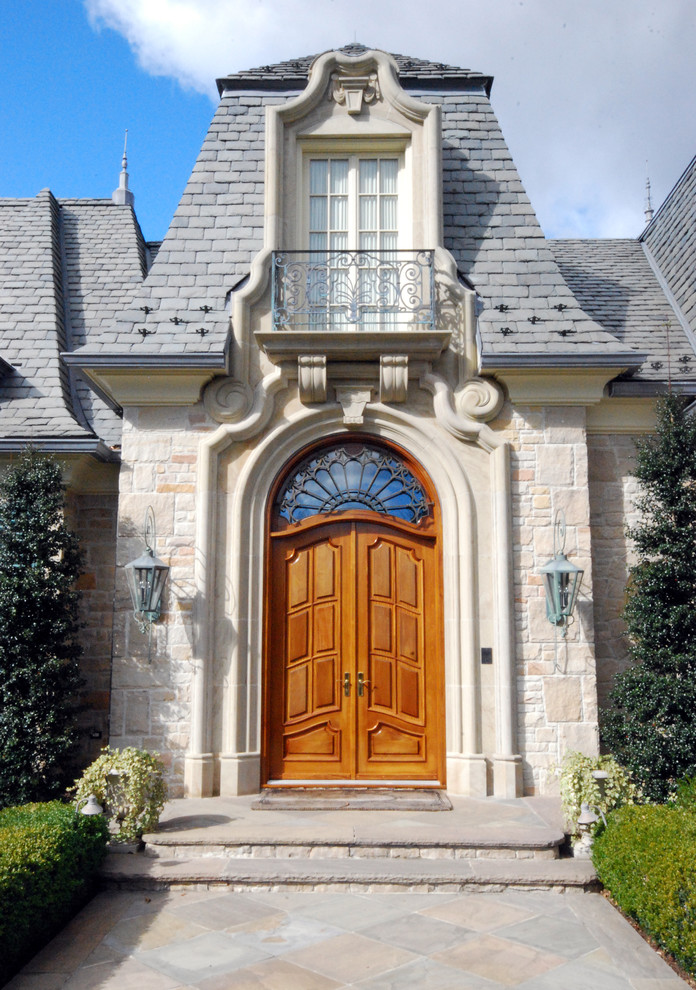 Réalisation d'une grande porte d'entrée tradition avec un sol en ardoise, une porte double et une porte en bois brun.