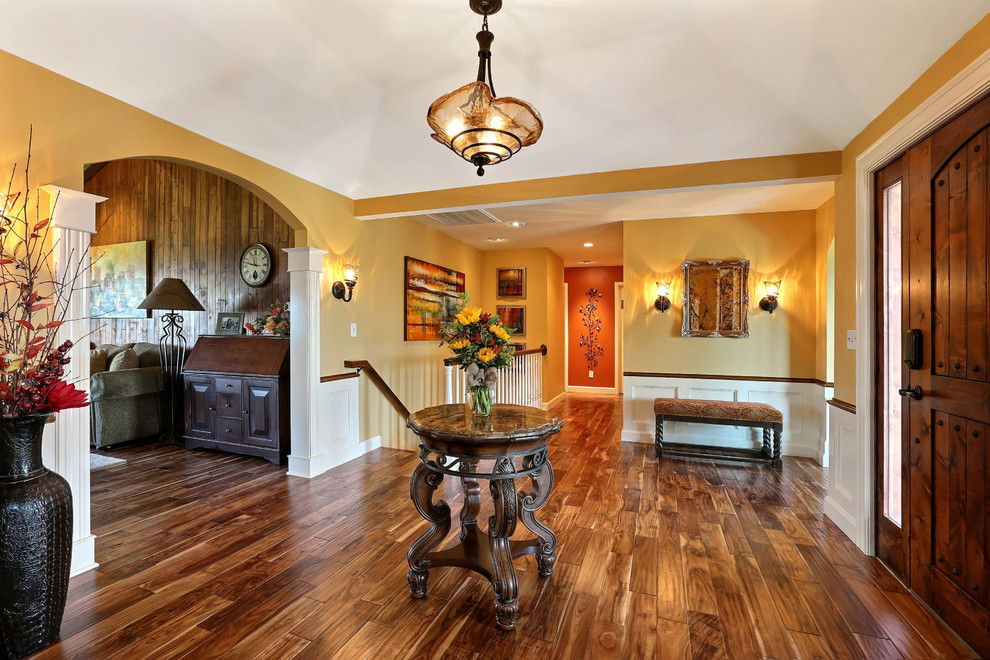 Design ideas for a large traditional foyer in Denver with yellow walls, dark hardwood flooring, a single front door and a dark wood front door.