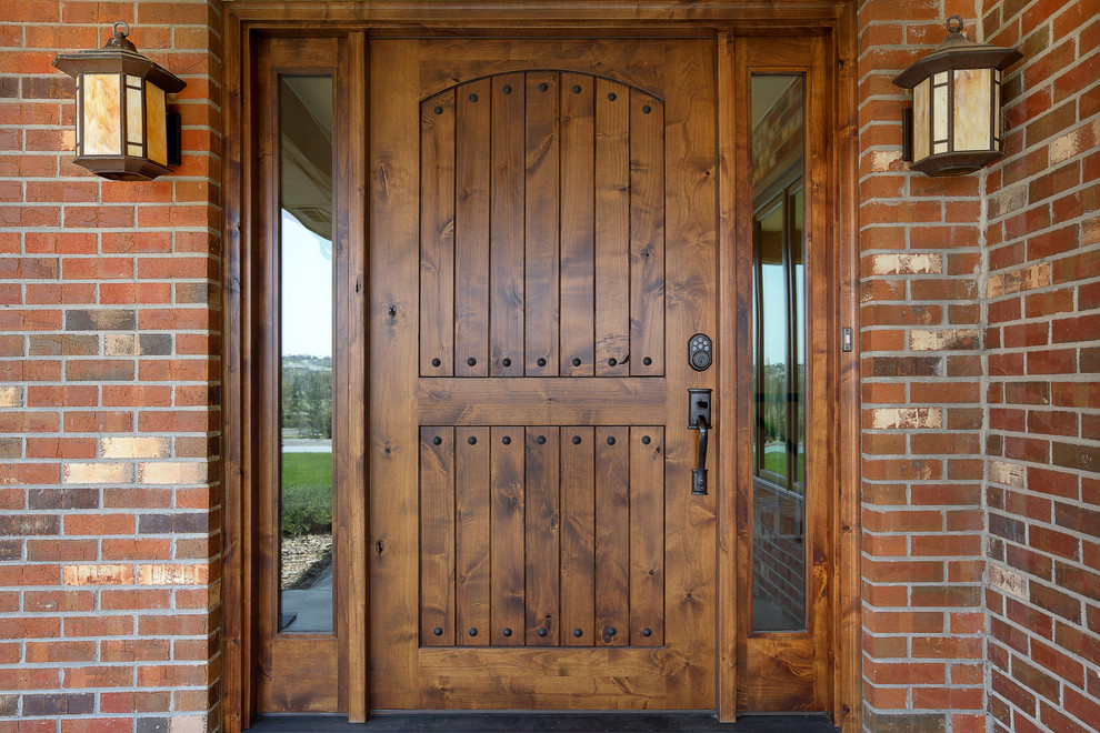 Modelo de puerta principal tradicional grande con paredes amarillas, suelo de madera oscura, puerta simple y puerta de madera oscura