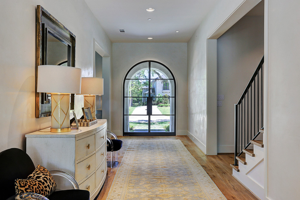 Modelo de hall clásico renovado con paredes blancas, suelo de madera en tonos medios, puerta doble, puerta de vidrio y suelo marrón