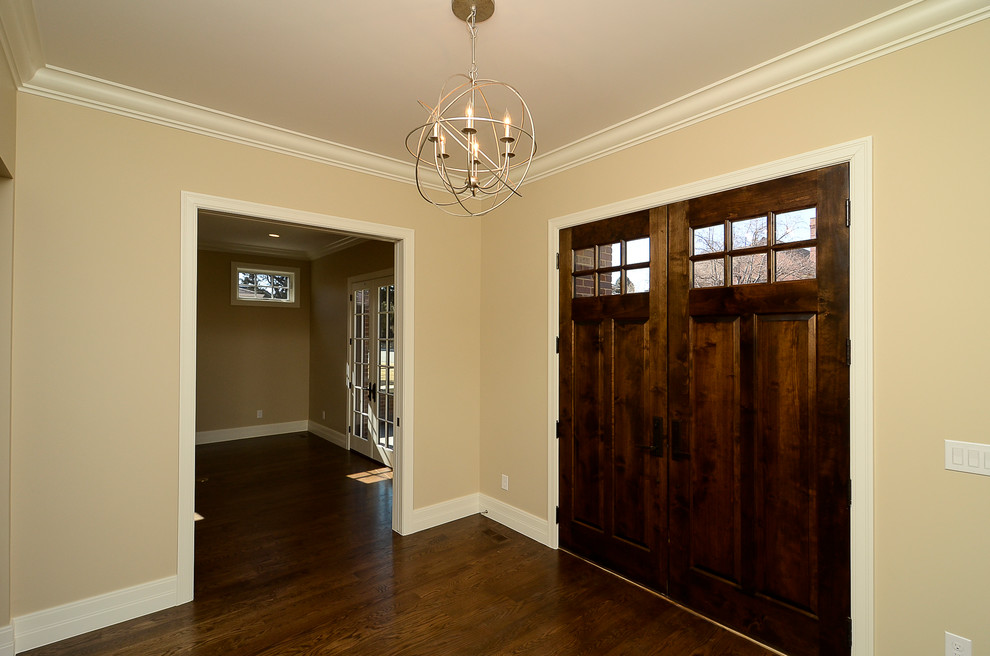 Idee per un grande ingresso tradizionale con pareti beige, pavimento in legno massello medio, una porta a due ante e una porta in legno bruno