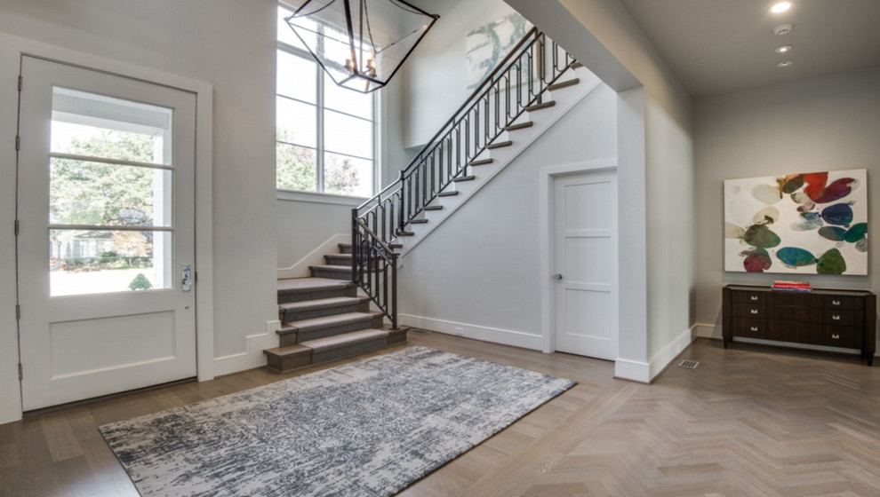 Large transitional medium tone wood floor and brown floor entryway photo in Dallas with gray walls and a white front door