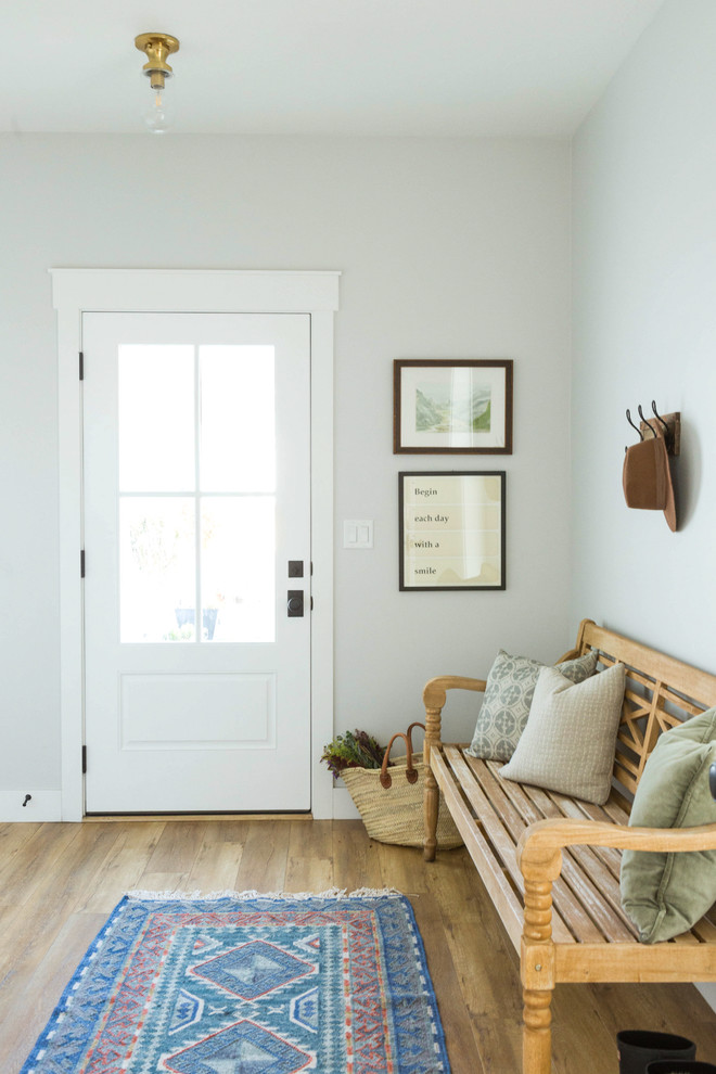 Example of a transitional medium tone wood floor and brown floor entryway design in Salt Lake City with white walls and a white front door