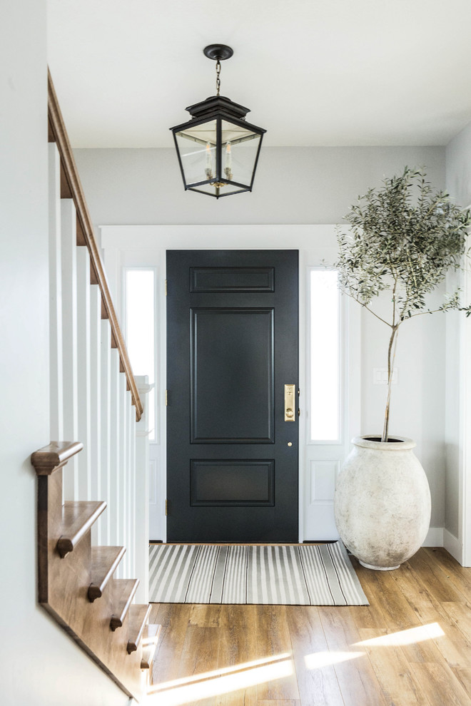Idee per una porta d'ingresso chic con pareti grigie, pavimento in legno massello medio, una porta singola, una porta nera e pavimento marrone