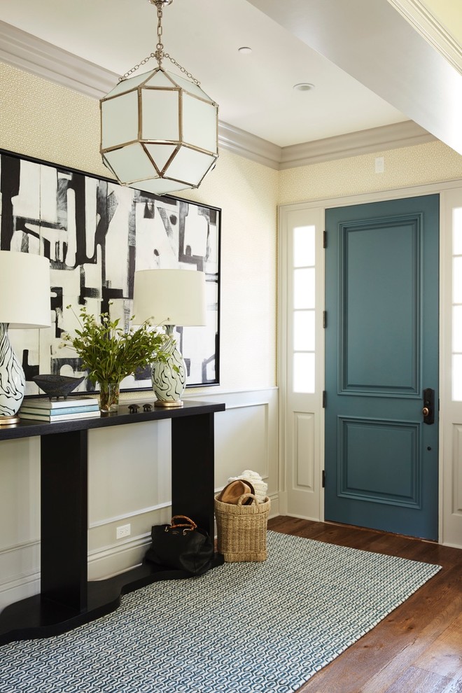 На фото: входная дверь: освещение в стиле неоклассика (современная классика) с бежевыми стенами, паркетным полом среднего тона, одностворчатой входной дверью и синей входной дверью с