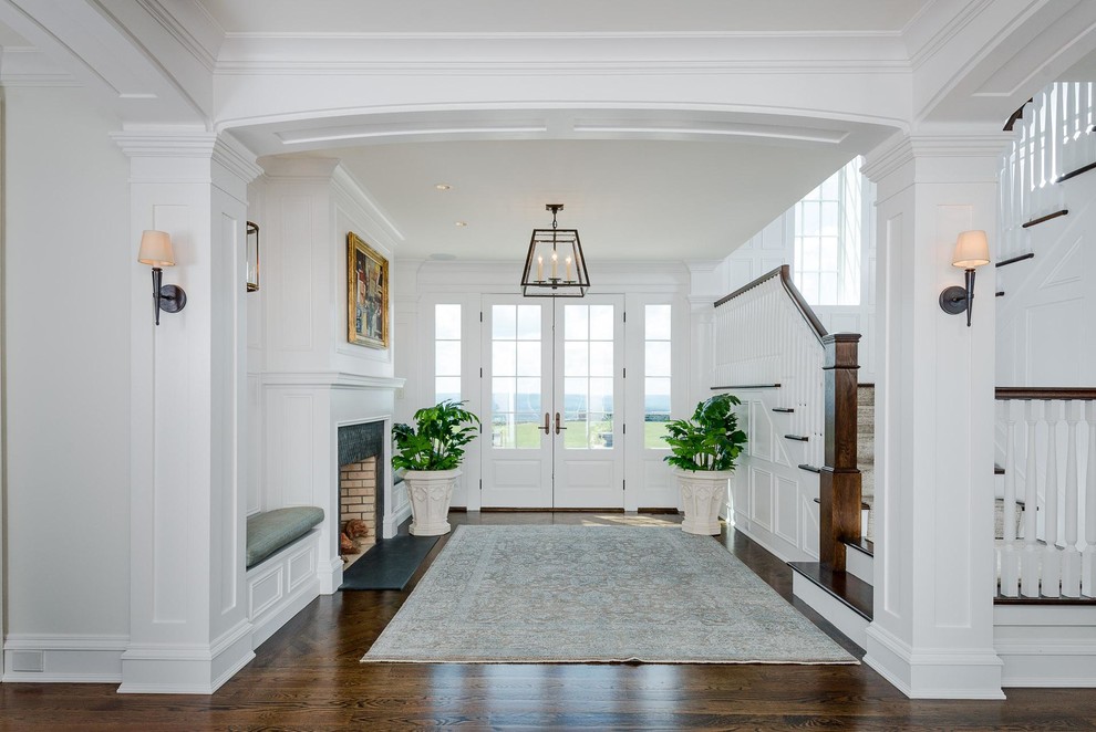 Geräumiges Klassisches Foyer mit dunklem Holzboden, Doppeltür, weißer Haustür, braunem Boden und weißer Wandfarbe in Sonstige