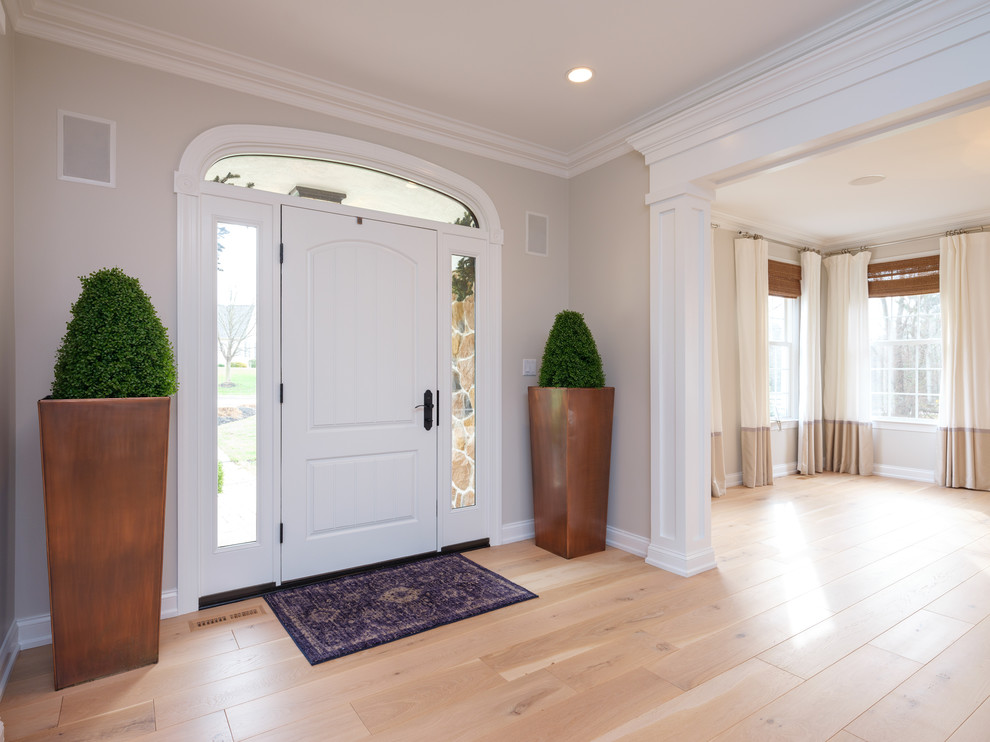 Cette image montre une porte d'entrée traditionnelle de taille moyenne avec un mur gris, parquet clair, une porte simple et une porte blanche.