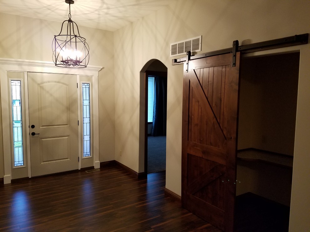 Diseño de puerta principal tradicional renovada de tamaño medio con paredes beige, suelo de madera oscura, puerta simple y puerta blanca