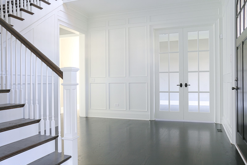 Свежая идея для дизайна: большое фойе в стиле неоклассика (современная классика) с белыми стенами, темным паркетным полом, одностворчатой входной дверью и черной входной дверью - отличное фото интерьера