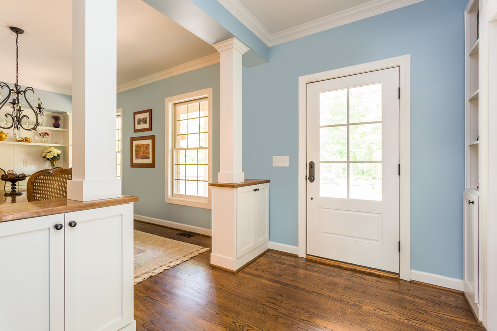 Idéer för en mellanstor amerikansk entré, med blå väggar, mörkt trägolv, en enkeldörr och en röd dörr