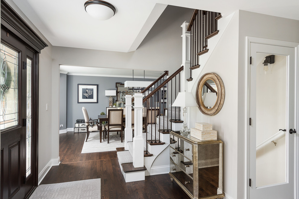 This is an example of a large traditional foyer in Chicago with grey walls, dark hardwood flooring, a pivot front door, a dark wood front door, brown floors and feature lighting.
