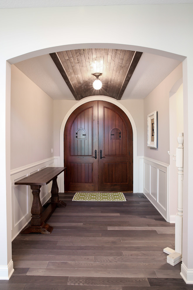 Cette image montre une porte d'entrée traditionnelle avec un mur gris, une porte double et une porte en bois foncé.