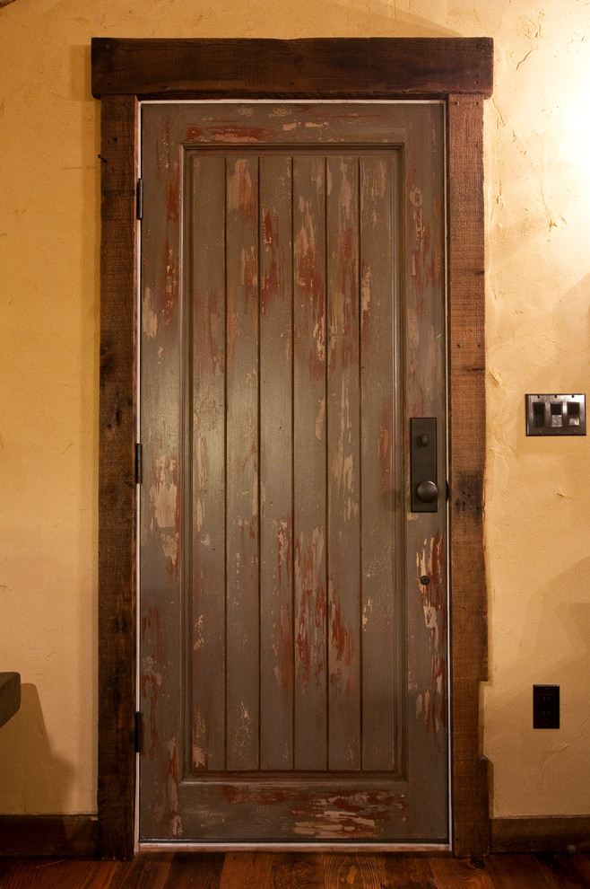 Immagine di una piccola porta d'ingresso rustica con pareti gialle, pavimento in legno massello medio, una porta singola e una porta grigia