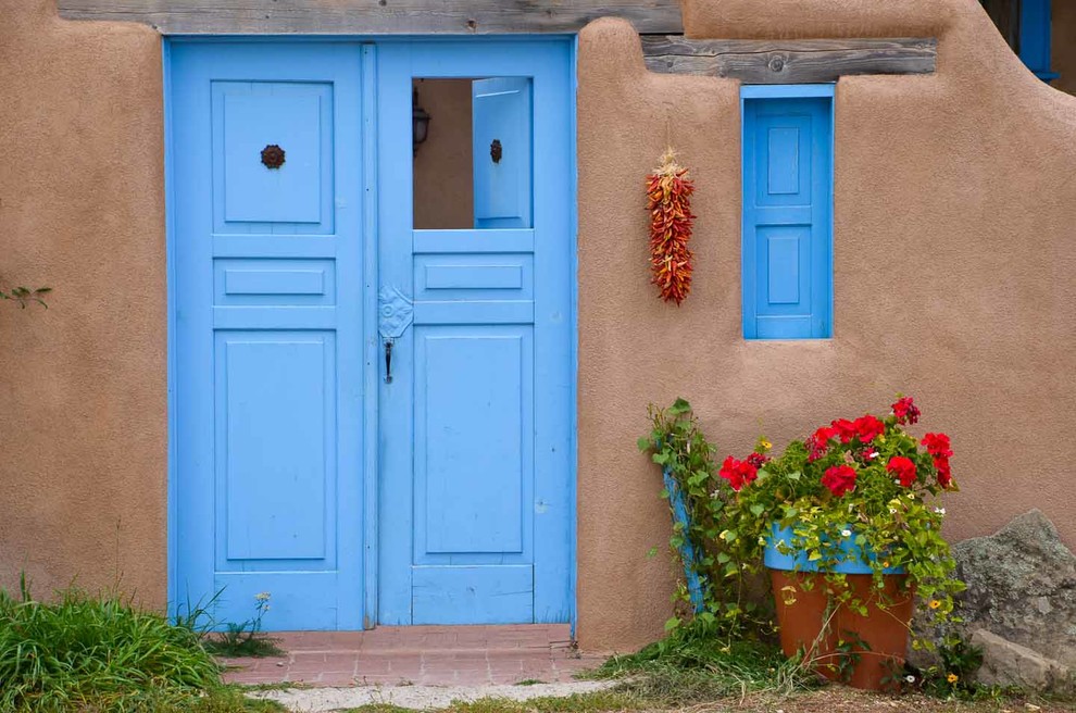 Cette image montre une porte d'entrée sud-ouest américain avec une porte double et une porte bleue.