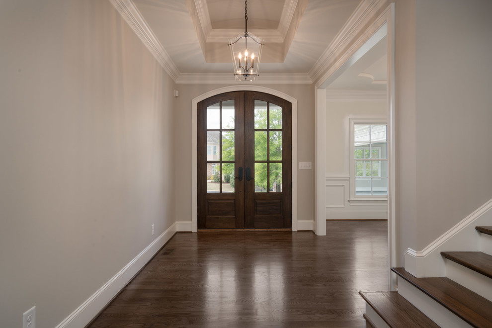Cette photo montre une grande entrée craftsman avec un mur gris, parquet foncé, une porte double et une porte marron.