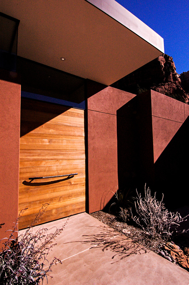 フェニックスにあるラグジュアリーな広いモダンスタイルのおしゃれな玄関ドア (赤い壁、コンクリートの床、木目調のドア) の写真