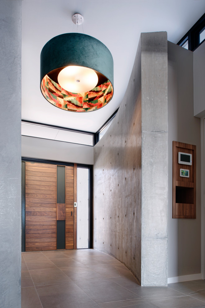 Imagen de hall minimalista de tamaño medio con paredes grises, puerta simple, puerta de madera en tonos medios y suelo gris