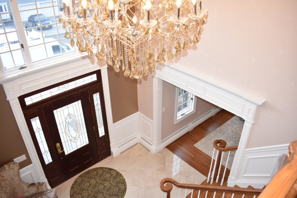 Mittelgroßes Klassisches Foyer mit beiger Wandfarbe, Marmorboden, Einzeltür, dunkler Holzhaustür und beigem Boden in New York