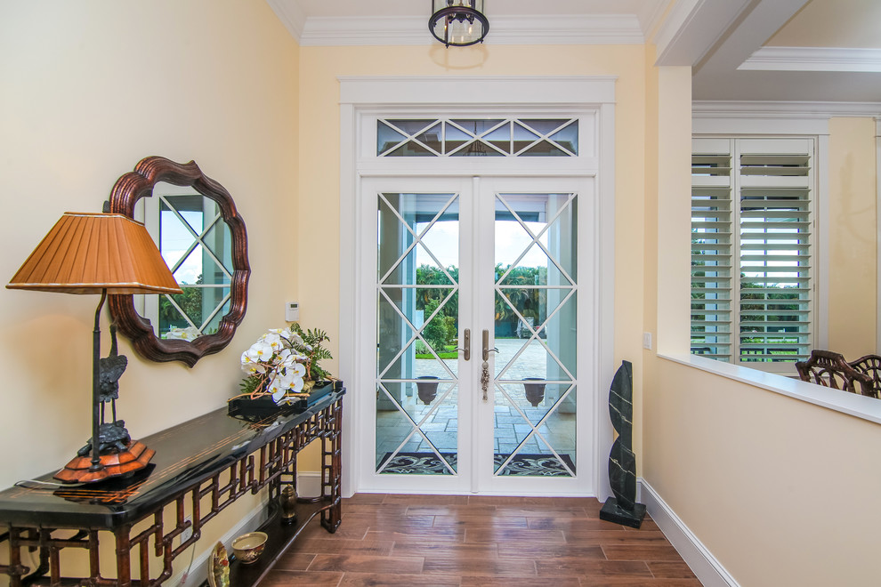 Kleiner Eingang mit Korridor, beiger Wandfarbe, dunklem Holzboden, Doppeltür und Haustür aus Glas in Miami