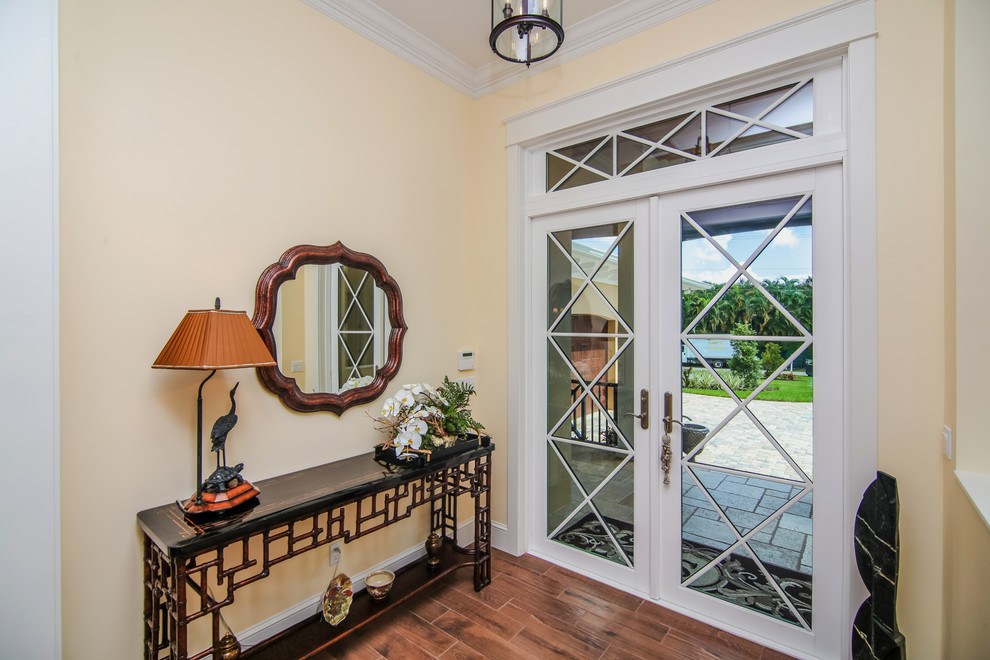 Foto de hall tropical pequeño con paredes beige, suelo de madera oscura, puerta doble y puerta de vidrio